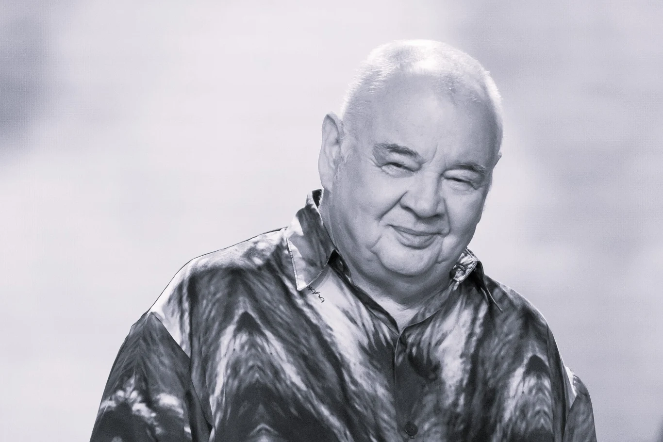 Nie żyje Stanisław Soyka Starszy mężczyzna o pogodnym wyrazie twarzy ubrany w koszulę z wzorem, patrzący na wprost, sfotografowany na neutralnym tle w odcieniach szarości.