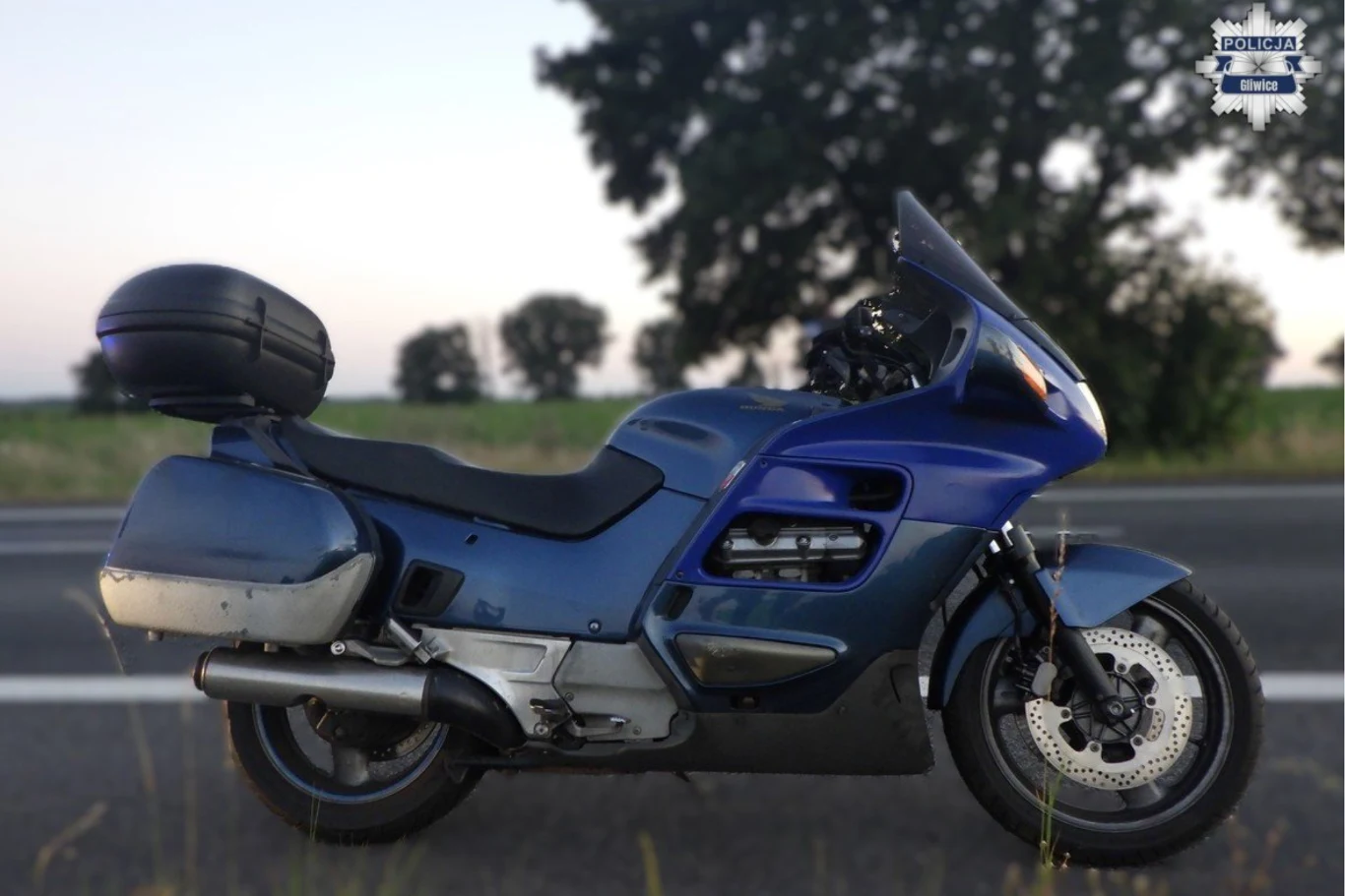 58-latek pomylił drogę. Policjantów zawiadomili inni użytkownicy ruchu drogowego. Granatowy motocykl turystyczny ustawiony na poboczu asfaltowej drogi, w tle rozmyte drzewa i spokojny krajobraz wiejski.