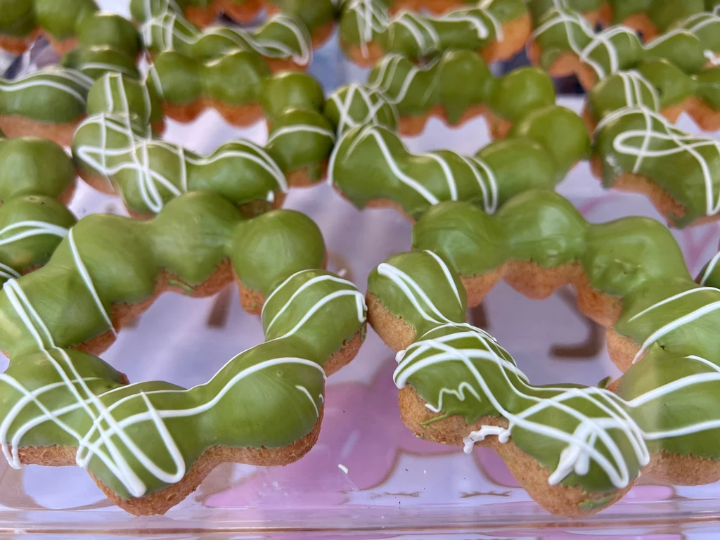 Słodycze z matchą są popularne Rząd zielonych donutów polanych polewą matcha z białymi dekoracjami z lukru, ułożonych na przezroczystej tacy
