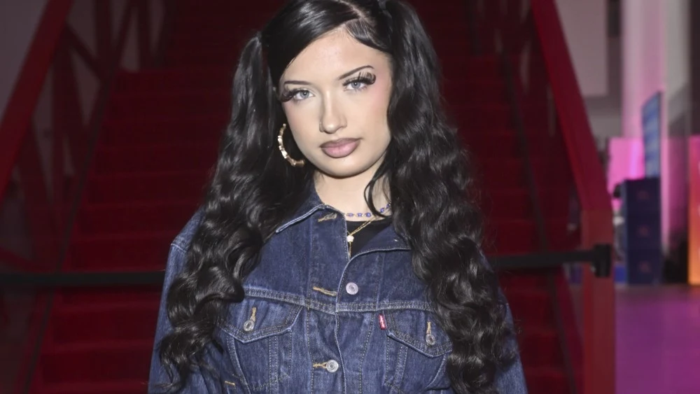 Viki Gabor Młoda kobieta z długimi, czarnymi włosami, spiętymi na dwa kucyki, ubrana w jeansową kurtkę, stoi na tle czerwonych schodów.