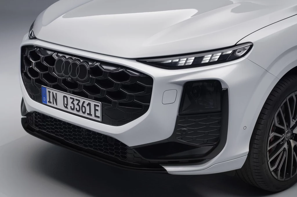 Z przodu Audi Q3 Sportback wygląda tak jak "klasyczne" Q3. Znajdziemy tutaj np. reflektory Matrix LED z modułem micro-LED. Przód białego samochodu marki Audi z charakterystycznym, dużym, czarnym grillem, nowoczesnymi reflektorami LED oraz tablicą rejestracyjną na tle szarego studia.