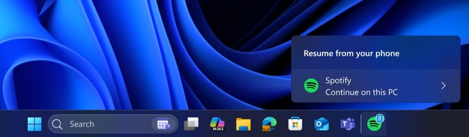 "Kontynuuj na komputerze". Wznawianie działania aplikacji Spotify z Androida na PC z Windows 11 Dolny pasek zadań systemu operacyjnego Windows z ikonami popularnych aplikacji, w prawym dolnym rogu powiadomienie dotyczące kontynuowania odtwarzania muzyki z aplikacji Spotify na tym komputerze.