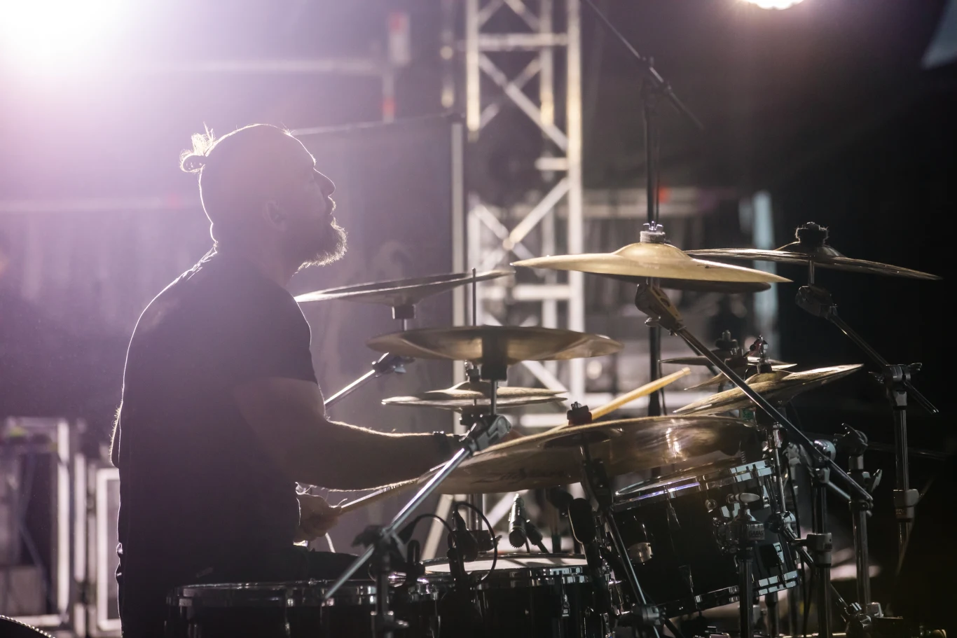 Flo Mounier jest liderem Cryptopsy Perkusista w czarnym ubraniu gra na dużym zestawie perkusyjnym na oświetlonej scenie koncertowej, światła sceniczne tworzą dynamiczną atmosferę występu.