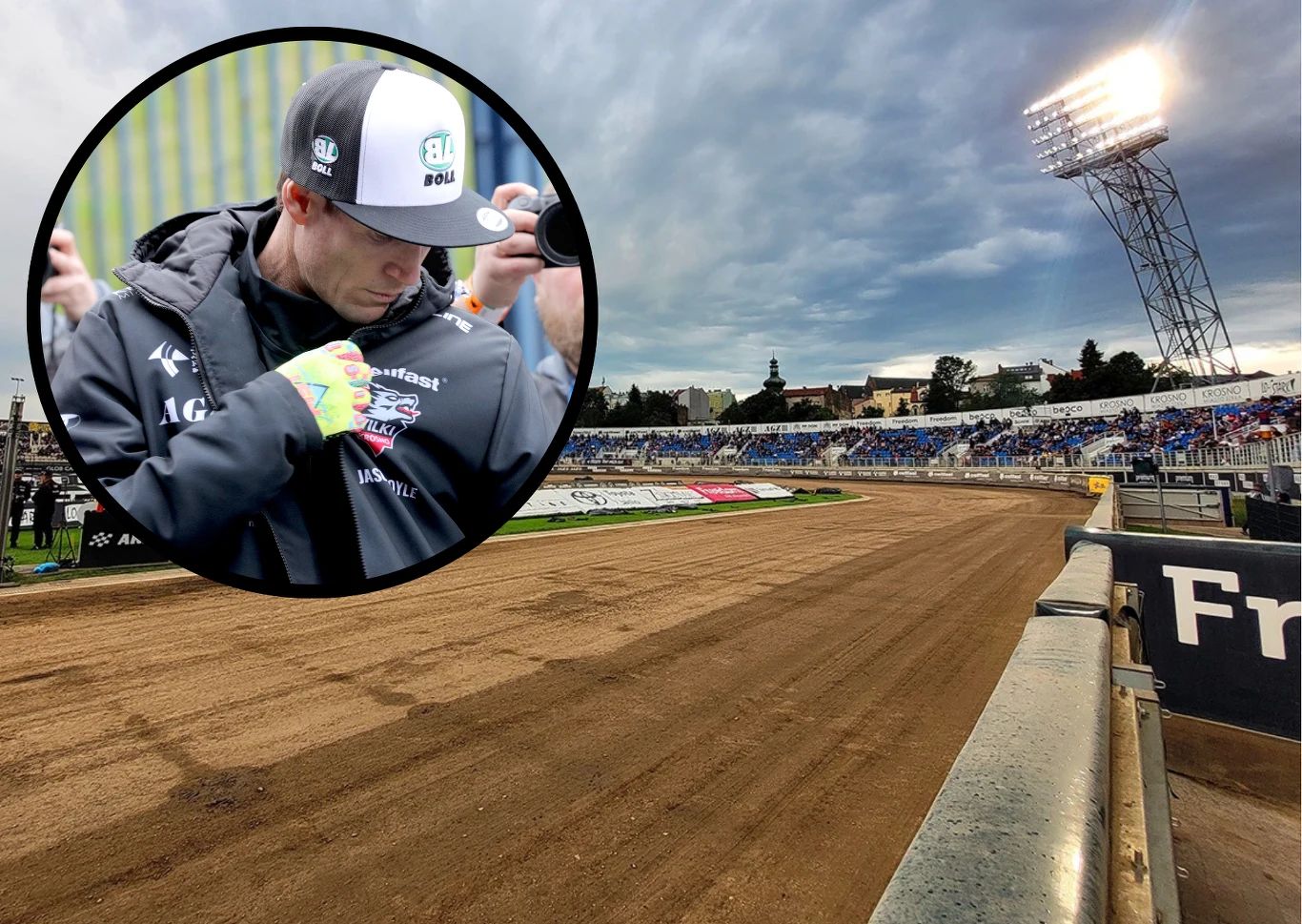 Wilki Krosno czekają na decyzję Jasona Doyle'a. Mistrz świata poważnie rozważa jazdę w Metalkas 2 Ekstralidze. Tor żużlowy z trybunami, na których znajdują się kibice, oświetlony reflektorem stadionowym, na pierwszym planie okrągłe powiększenie pokazujące sportowca w czapce z daszkiem, skupionego na podpisywaniu lub oglądaniu rękawicy.