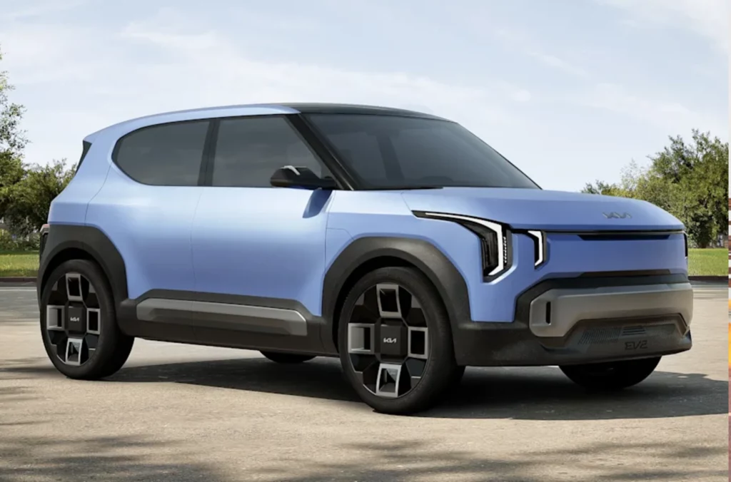 EV2 to mały crossover, który stanie się podstawowym modelem elektrycznym w ofercie Kii na rynku europejskim. Nowoczesny, niebieski samochód typu SUV o dynamicznym kształcie karoserii i charakterystycznych reflektorach LED, zaparkowany na asfaltowej nawierzchni w otoczeniu zieleni.