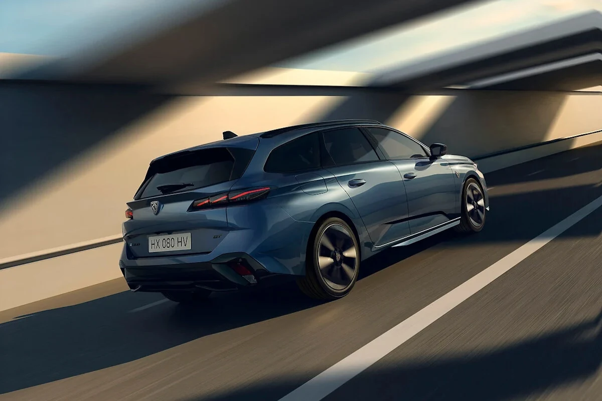 Peugeot 308 SW po liftingu. Z tyłu zmiany nie są spektakularne Nowoczesny niebieski samochód typu kombi poruszający się dynamicznie po dobrze oświetlonej drodze w tunelu lub pod wiaduktem, z widocznym ruchem i światłami podkreślającymi aerodynamiczne linie pojazdu.