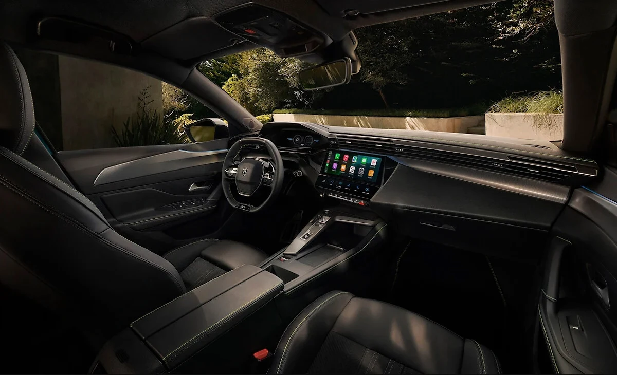 W kabinie znajdziemy szereg nowych materiałów wysokiej jakości Nowoczesne wnętrze samochodu z zaawansowanymi systemami multimedialnymi na środkowym ekranie, sportowa kierownica oraz wygodne, skórzane siedzenia, całość utrzymana w ciemnej tonacji z niewielką ilością światła wpadającego przez okna.