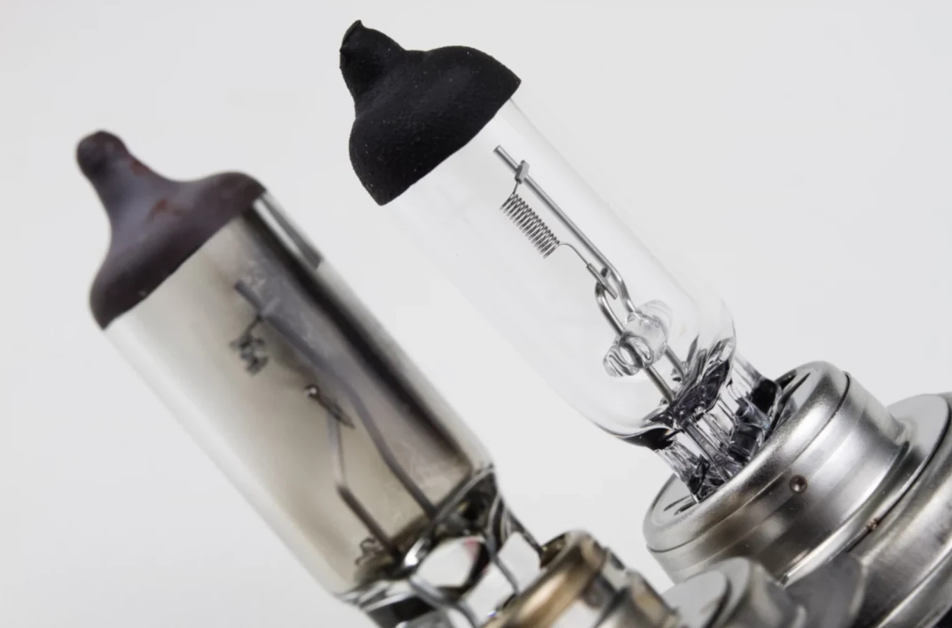 Retrofity LED w starszych autach już legalne. Nowe przepisy UE Dwie żarówki halogenowe umieszczone blisko siebie, widoczne szczegóły konstrukcji żarnika i metalowych elementów wewnątrz szklanej obudowy, tło jasnoszare.