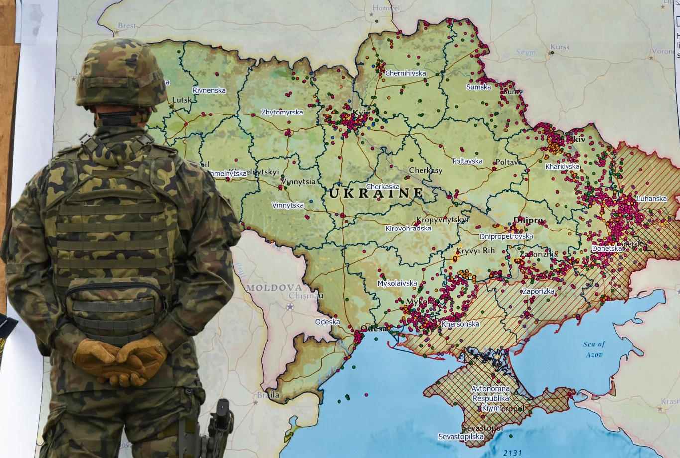 Zachodni sojusznicy przygotowali plan obrony Ukrainy na okres po wojnie z Rosją Żołnierz w mundurze kamuflażowym stoi tyłem, obserwując dużą mapę Ukrainy z zaznaczonymi licznymi punktami, prawdopodobnie symbolizującymi miejsca istotnych wydarzeń lub konfliktów