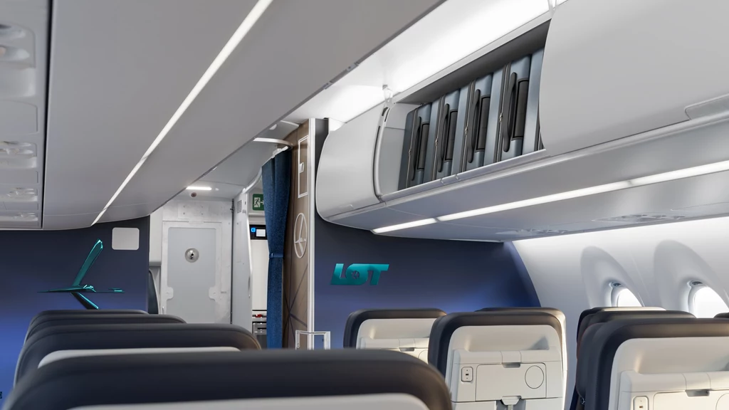 Schowki w A220 mają zapewnić szybszy boarding. Wnętrze samolotu pasażerskiego z rzędami siedzeń, zamkniętymi schowkami bagażowymi nad głowami oraz widocznym logo LOT na niebieskiej ścianie w przedniej części kabiny. A220 LOT