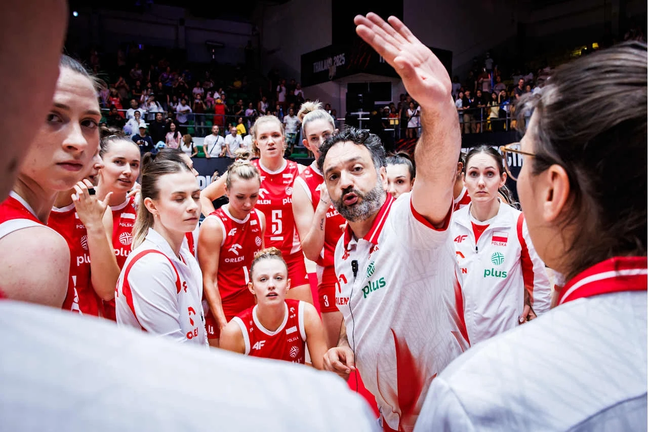 MŚ siatkarek. Stefano Lavarini i reprezentacja Polski Trener udziela wskazówek zawodniczkom drużyny siatkarskiej podczas przerwy w meczu, zawodniczki ubrane w czerwone i białe stroje skupione wokół niego, atmosfera pełna koncentracji i zaangażowania.