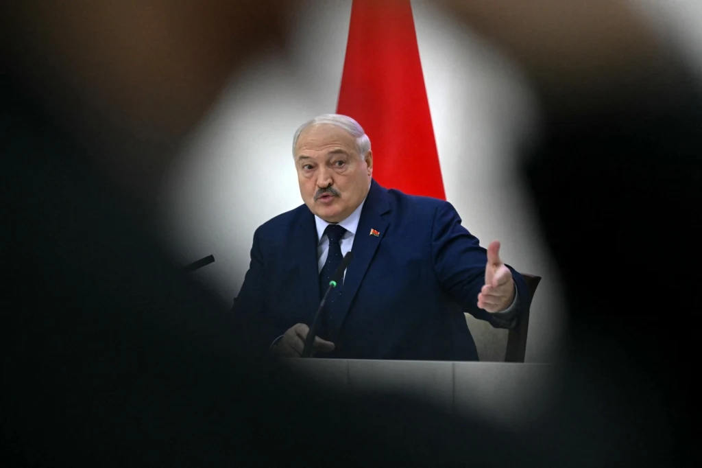 Przeciwnik Łukaszenki zaginął w tajemniczych okolicznościach Mężczyzna w garniturze przemawia przy stole, gestykulując dłonią w kierunku publiczności; w tle widoczna czerwona flaga.