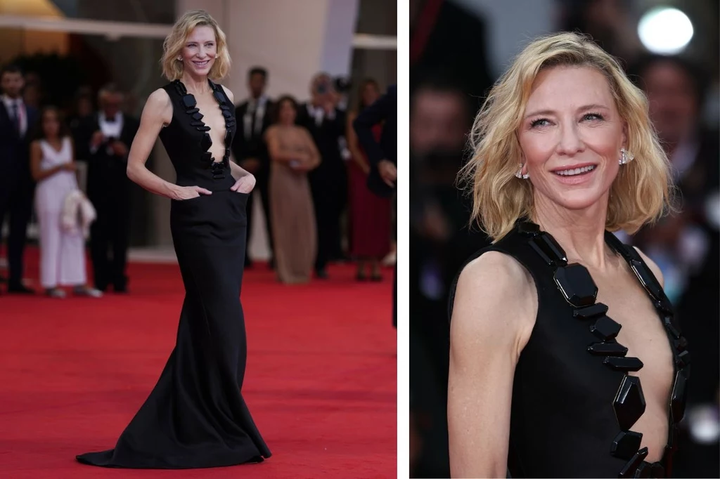 Cate Blanchett olśniła na festiwalu w Wenecji Elegancka kobieta w długiej czarnej sukni z szerokim dekoltem i ozdobnym kołnierzem stojąca na czerwonym dywanie, uśmiechnięta, wokół tłum ludzi obserwujących wydarzenie.