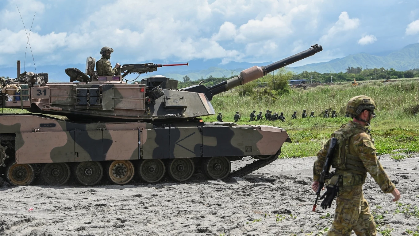 Australia wsparła Ukrainę aż 45 czołgami Abrams Czołg z żołnierzami na otwartym terenie, w tle formacja kolejnych wojskowych oraz żołnierz idący na pierwszym planie w pełnym umundurowaniu.