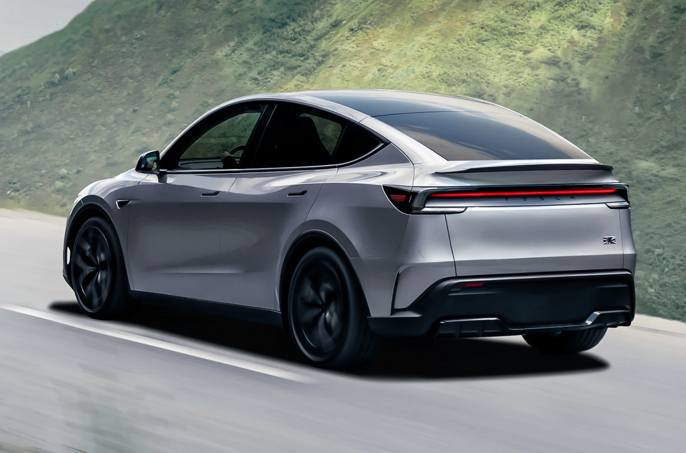 Model Y Performance można już skonfigurować na polskiej stronie Tesli Srebrny samochód elektryczny o nowoczesnym designie jedzie po asfaltowej drodze, w tle widoczny zielony pagórek. Auto ma wyraźnie zarysowane linie, ciemne, przyciemniane szyby i czarne felgi.