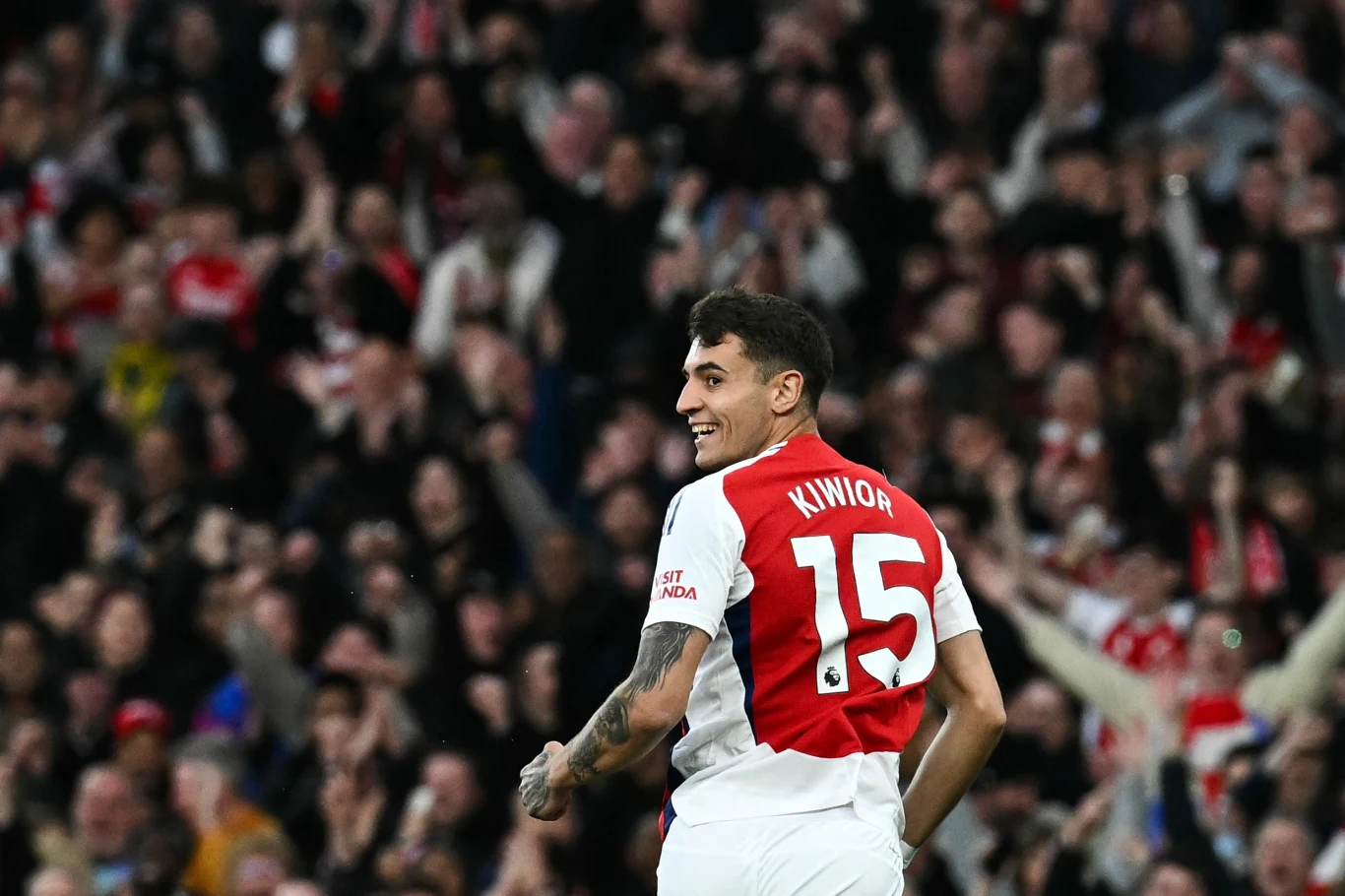 Jakub Kiwior Piłkarz w stroju meczowym z numerem 15 na plecach i nazwiskiem Kiwior, otoczony przez wiwatujących kibiców na trybunach stadionu.