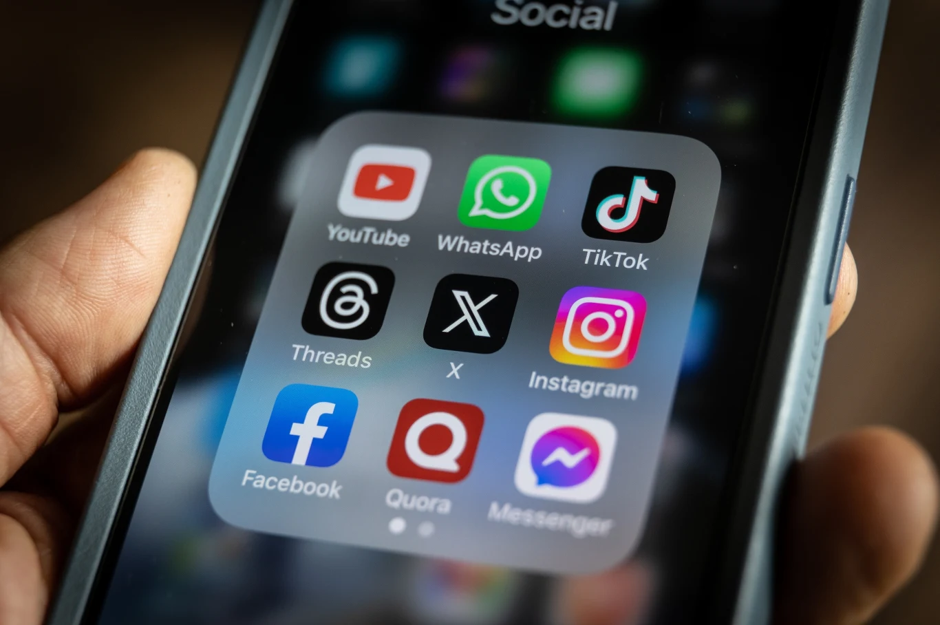 Media społecznościowe przyciągają nowych użytkowników. Które są najpopularniejsze? Ekran smartfona ukazujący folder z popularnymi mediami społecznościowymi, takimi jak YouTube, WhatsApp, TikTok, Threads, X, Instagram, Facebook, Quora i Messenger.