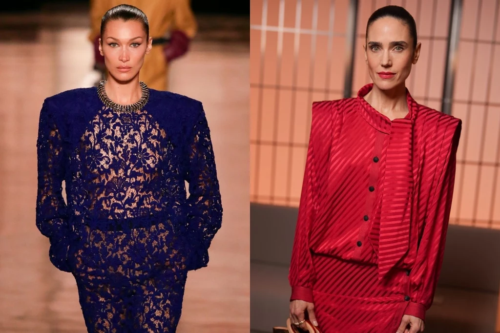 Saint Laurent, Louis Vuitton. Ph: WWD, Antoine Flament Dwie kobiety ubrane w eleganckie stroje, jedna w koronkowym niebieskim garniturze z szerokimi ramionami, druga w czerwonym, marynarkowym stroju z podkreślonymi ramionami, obie mają spięte włosy.