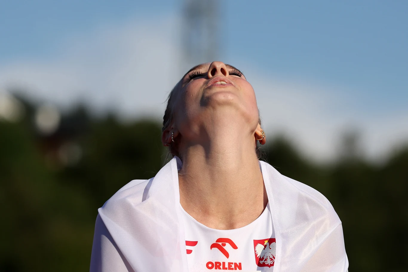 Alicja Sielska Sportowiec w stroju z polską flagą i logotypem Orlen, unosi głowę do góry, wyrażając silne emocje po zakończeniu rywalizacji.