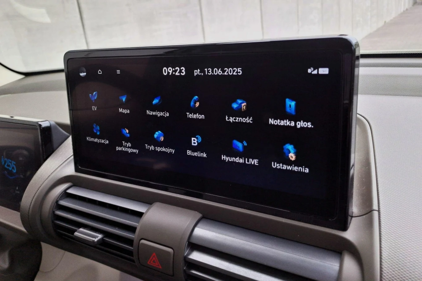 Menu systemu multimediów jest proste i intuicyjne. Ekran systemu multimedialnego w samochodzie wyświetlający menu z ikonami takich funkcji jak mapa, nawigacja, telefon, notatka głosowa, klimatyzacja, ustawienia oraz inne opcje pojazdu. Poniżej ekranu widoczne są kratki nawiewów oraz ostrzegawcze świate...