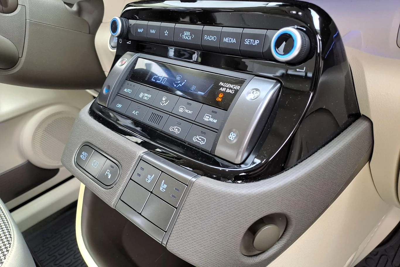 Hyundai pozostawił w Insterze sporo fizycznych przycisków. Nie da się ukryć, że jest to dużo wygodniejsze rozwiązanie niż sterowanie przez ekran multimediów. Panel sterowania klimatyzacją, ogrzewaniem i systemem multimedialnym w nowoczesnym samochodzie, z czytelnymi przyciskami, wyświetlaczem LCD oraz podświetleniem, otoczony jasnym wnętrzem pojazdu.