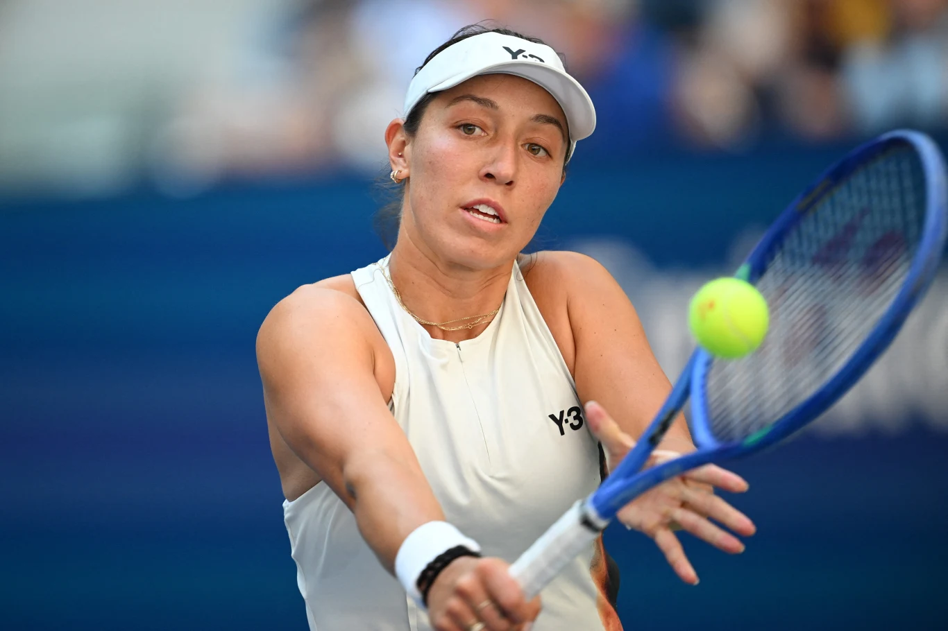 Jessica Pegula Tenisistka w białym stroju odbija piłkę rakietą podczas meczu tenisowego, w tle widoczna rozmyta trybuna.