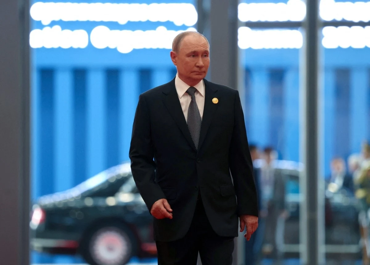 Władimir Putin na szczycie Szanghajskiej Organizacji Współpracy Mężczyzna w garniturze idzie w dobrze oświetlonym budynku, w tle widoczny jest czarny samochód oraz zaszklone drzwi z odbijającym się światłem.