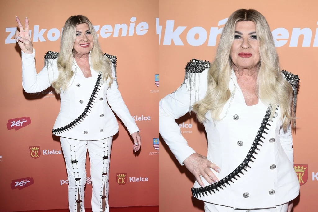 Kobieta z długimi blond włosami w białym, stylowym garniturze z ozdobnymi ćwiekami i zamkami, pozuje na tle pomarańczowej ścianki z napisami oraz logotypami sponsorów i miasta Kielce; na jednym ze zdjęć pokazuje gest pokoju.