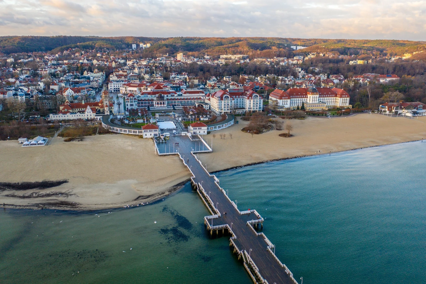 Sopot był nazywany "polską Ibizą". Dziś kieruje ofertę dla rodzin z dziećmi i seniorów. Panorama Sopotu z loku ptaka - morze, molu, plaża i budynki.