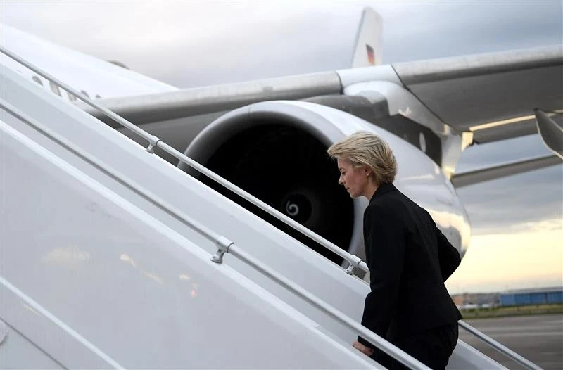 Lot Ursuli von der Leyen zakłócony Kobieta w eleganckim stroju wchodzi po schodach do samolotu pasażerskiego, w tle widoczny jest silnik odrzutowca oraz fragment skrzydła.