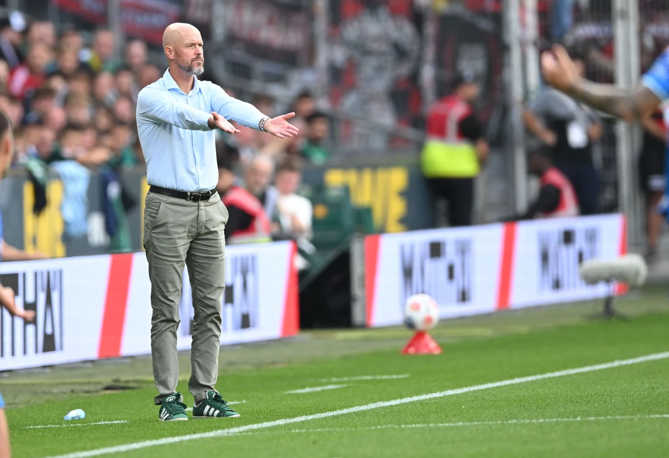 Erik ten Hag został zwolniony z Bayeru Leverkusen po zaledwie dwóch meczach Bundesligi Trener piłkarski gestykuluje na linii bocznej boiska podczas meczu, w tle widzowie na trybunach oraz banery reklamowe.