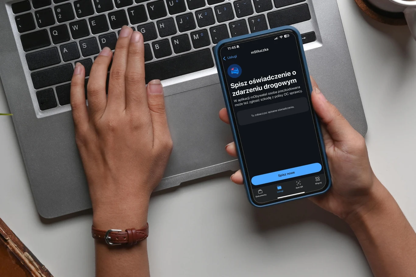 Od 1 września w mObywatelu działa usługa mStłuczka. Docelowo ma pomóc milionom polskich kierowców Ręce osoby korzystającej z laptopa i trzymającej w drugiej dłoni smartfon z włączoną aplikacją do spisywania oświadczenia o zdarzeniu drogowym.