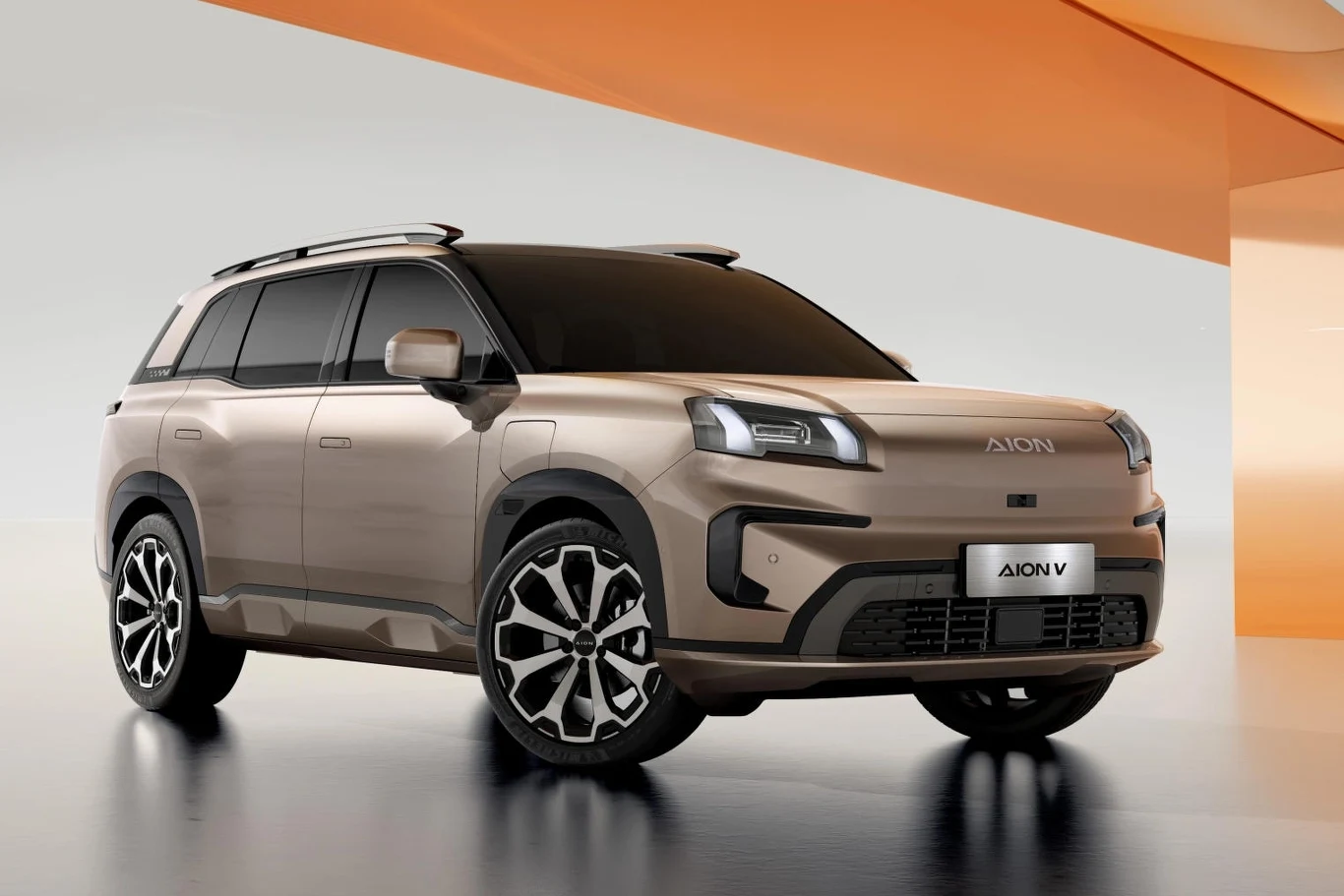 Nowoczesny SUV Aion V w kolorze beżowym ustawiony w jasnym, minimalistycznym wnętrzu, wyróżniający się dużymi, designerskimi felgami, wyrazistymi światłami przednimi oraz aerodynamiczną sylwetką.