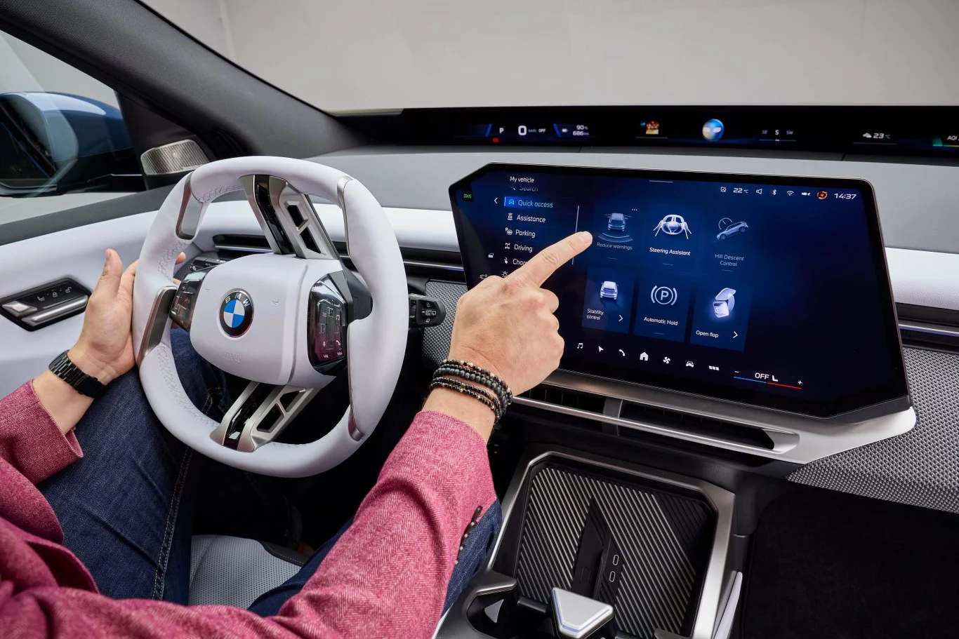 Kokpit nowoczesnego samochodu BMW z zaawansowanym panelem dotykowym, na którym użytkownik wybiera opcje multimedialne, a wnętrze wyróżnia się innowacyjnym designem i wysoką jakością wykończenia.