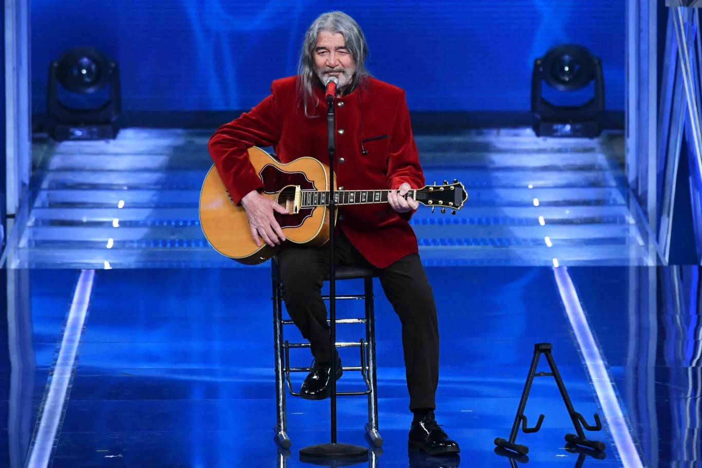 Drupi zadebiutował w filmie Mężczyzna z długimi, siwymi włosami siedzi na krześle na scenie, grając na gitarze akustycznej i śpiewając do mikrofonu; ubrany jest w czerwony, welurowy żakiet, a w tle widoczna jest niebieska aranżacja świetlna.