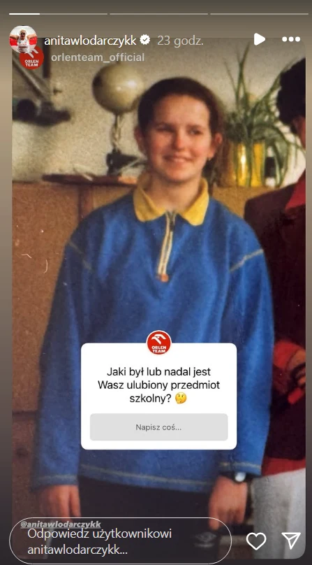 Anita Włodarczyk sprzed lat Młoda dziewczyna w niebieskiej bluzie z żółtym kołnierzem stoi wewnątrz pomieszczenia na tle mebli oraz zielonej rośliny doniczkowej, obok widoczny fragment innej osoby; na zdjęciu znajduje się pole z pytaniem o ulubiony szkolny przedmiot.
