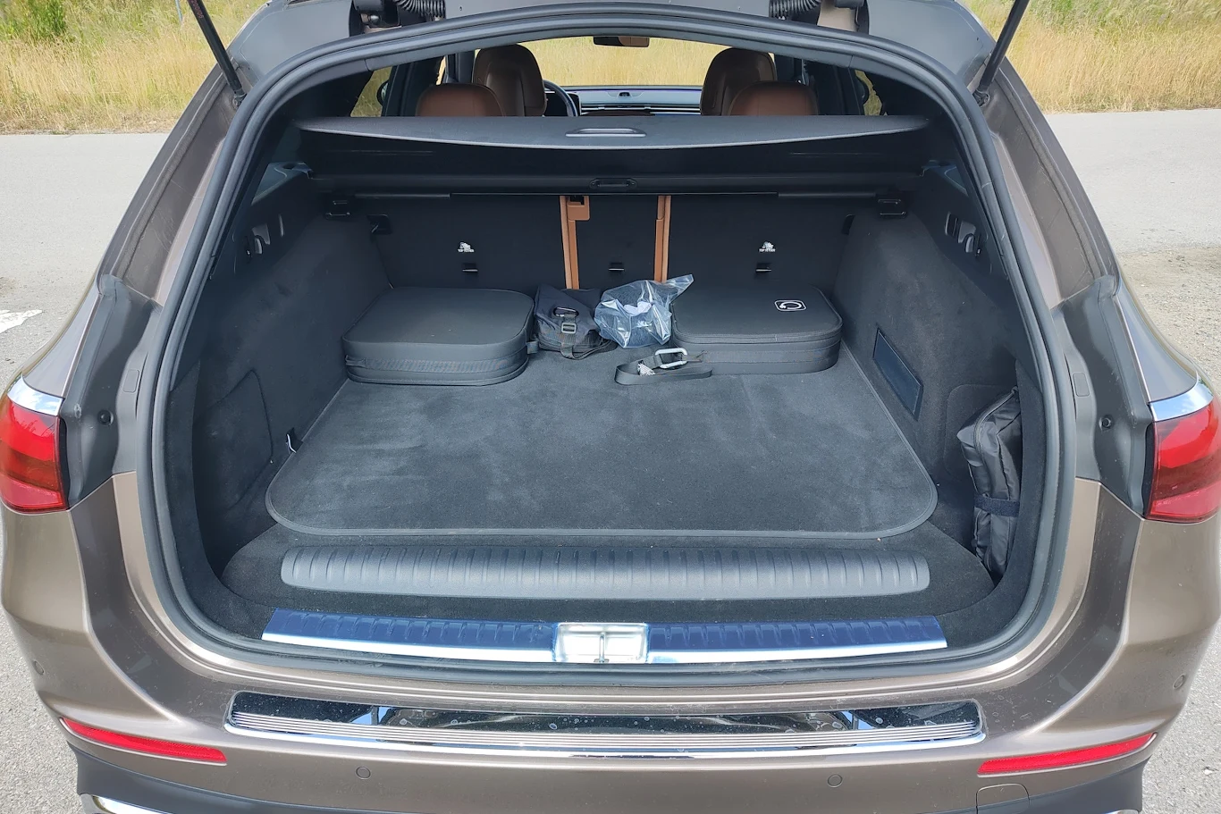 Otwarty bagażnik samochodu typu SUV, w którym znajdują się dwie walizki, torba i plastikowa siatka, wnętrze przestronne i czyste.