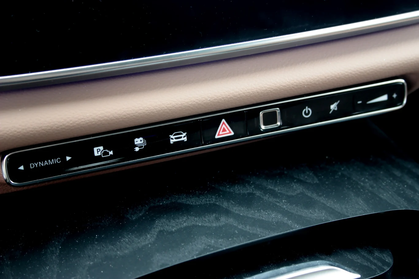 Panel sterowania samochodowego z przyciskami do uruchamiania różnych funkcji pojazdu, w tym trybu dynamicznego, czujników parkowania, systemu kamer, świateł awaryjnych i innych funkcji wspomagających kierowcę, osadzony w nowoczesnym wnętrzu pojazdu.