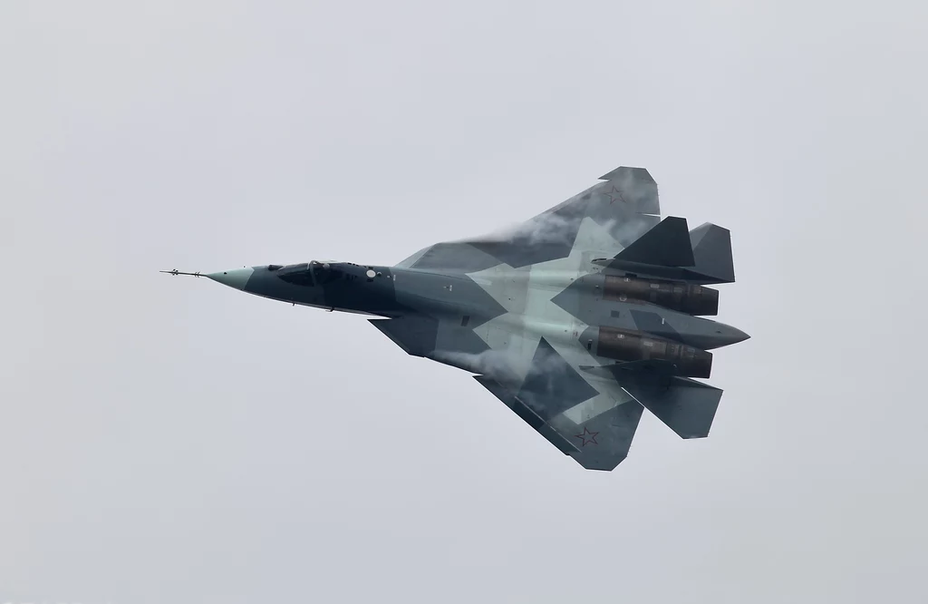 Rosyjski myśliwiec Su-57 to jedna z najgroźniejszych maszyn wojennych Rosjan. Polski SPL może go wykryć Wojskowy myśliwiec odrzutowy w locie na tle szarego, zachmurzonego nieba, maszyna w kamuflażu, widoczne detale konstrukcji oraz dysze silników.