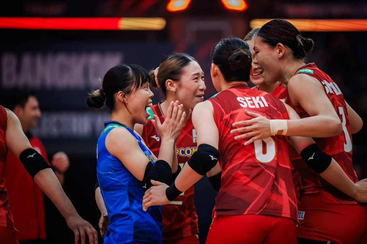 Siatkarki reprezentacji Japonii wyeliminowały z turnieju Holandię Grupa siatkarek w sportowych strojach cieszy się po udanej akcji na boisku, otaczając się radośnie i wymieniając uśmiechy, ich emocje podkreśla gestykulacja i kontakt wzrokowy.