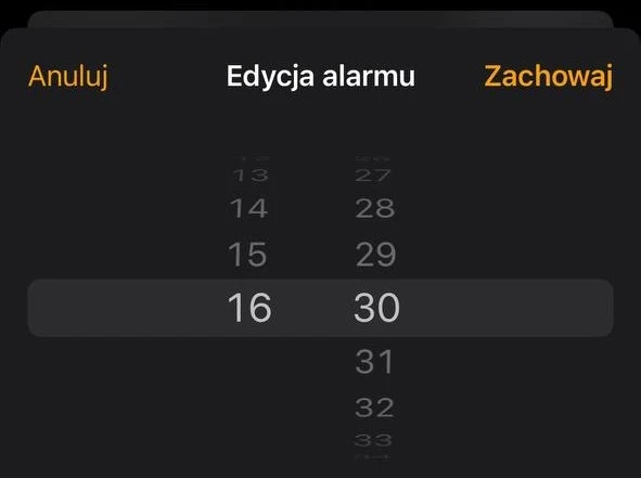 Interfejs ustawiania alarmu w aplikacji na smartfonie z wyświetlonymi godzinami i minutami oraz przyciskami anulowania i zapisu.