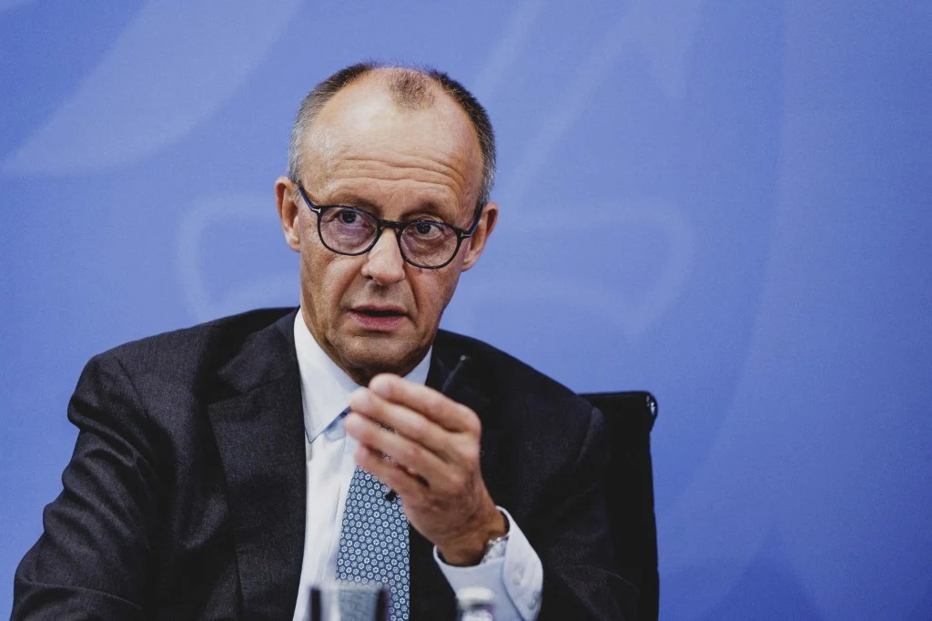 Friedrich Merz zapowiedział, że nie wyśle niemieckiego wojska do Ukrainy Mężczyzna w średnim wieku w garniturze i okularach, siedzi przy stole w trakcie oficjalnego wystąpienia lub konferencji, wykonując gest dłonią, w tle niebieskie tło o jednolitej kolorystyce.