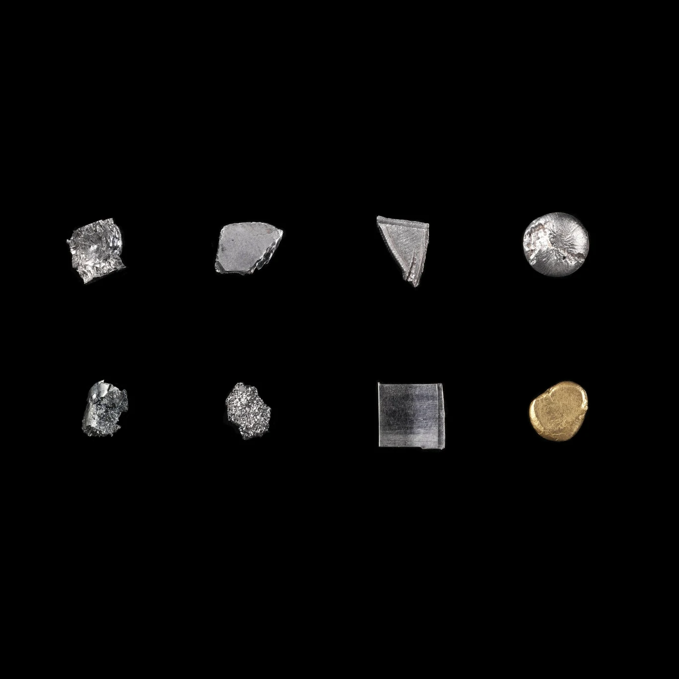 Osiem kawałków różnych metali w różnych kształtach i kolorach ułożonych w dwóch rzędach na czarnym tle, jeden z fragmentów jest złoty, pozostałe mają odcień srebrny.