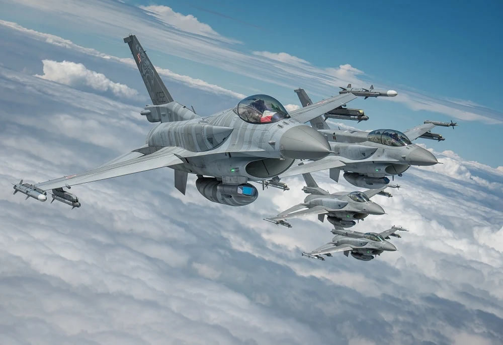 Polski system obrony powietrznej to miks wielu elementów. Oto z czego się składa Formacja kilku myśliwców wojskowych F-16 lecących nad warstwą chmur na tle nieba, maszyny widoczne z bliska, dobrze przedstawione szczegóły kadłuba i uzbrojenia.