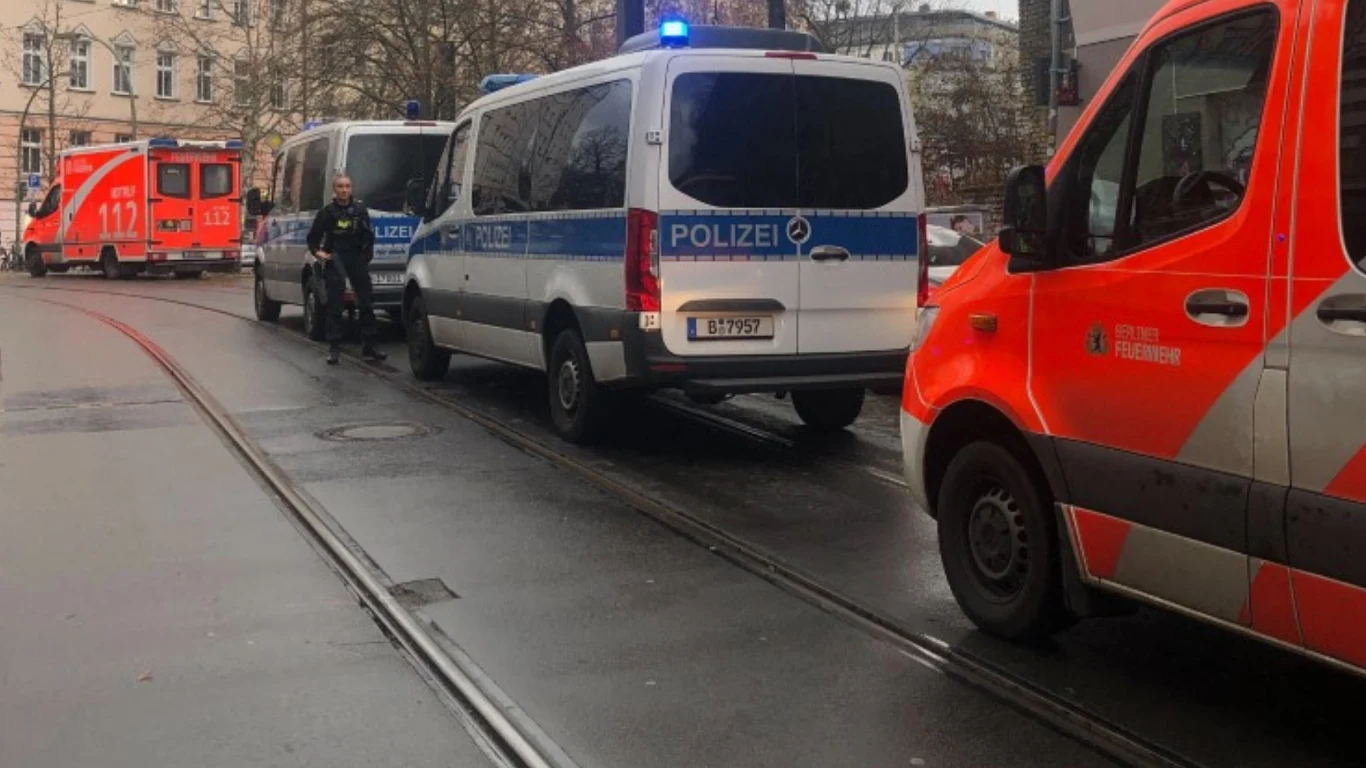Poważne zdarzenie w Berlinie. Samochód wjechał w ludzi (zdj. ilustracyjne) Karetka pogotowia oraz dwa radiowozy policji parkują na ulicy wzdłuż torów tramwajowych, obok znajduje się funkcjonariusz policji, w tle widoczne są inne zabudowania miasta.