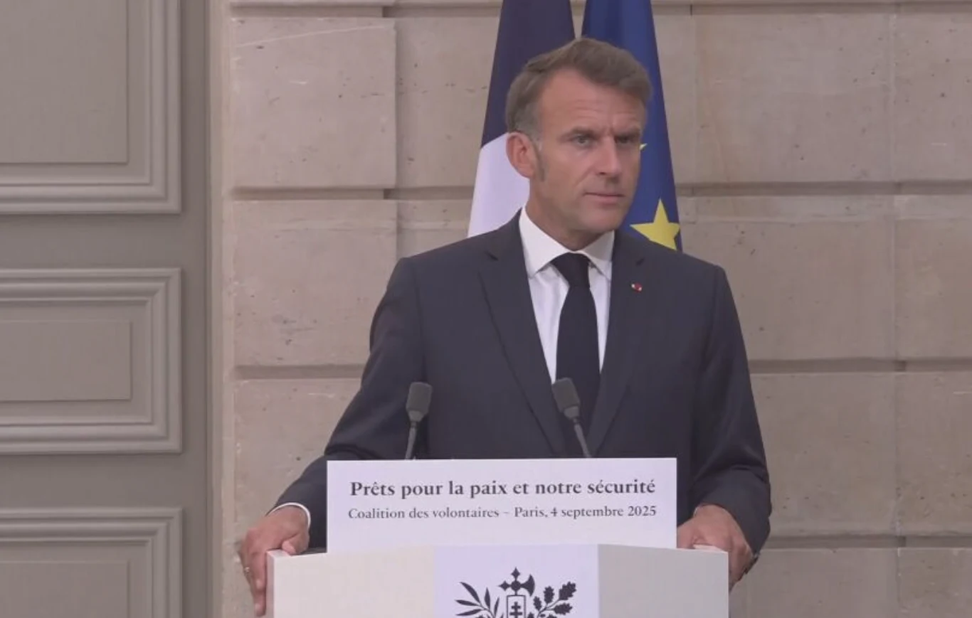 "Koalicja chętnych" i ustalenia ws. Ukrainy. Emmanuel Macron zabrał głos Mężczyzna w garniturze stoi za mównicą podczas oficjalnej konferencji prasowej, w tle widoczne flagi Francji i Unii Europejskiej, na mównicy znajduje się napis dotyczący pokoju i bezpieczeństwa.