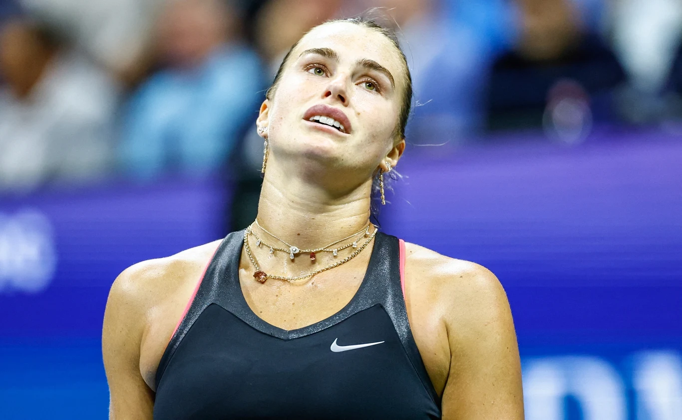 Aryna Sabalenka rywalizowała z Jessicą Pegulą o awans do finału US Open Kobieta w sportowym stroju podczas meczu tenisowego, widoczna emocja na jej twarzy, lekko pochylona głowa, tło rozmyte z elementami kortu i publiczności.