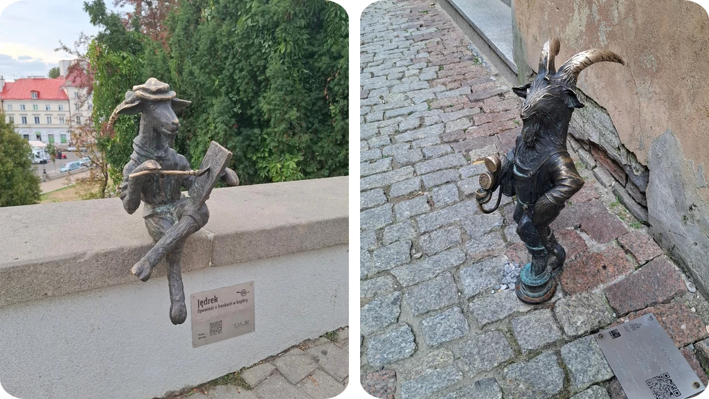 Dwie małe rzeźby kozłów z brązu; jedna siedzi na murku i trzyma otwartą księgę wraz z przyrządem do pisania, druga stoi na bruku w pozie jakby coś ogłaszała, trzymając megafon; obie mają na sobie kapelusze i są ustawione przy tabliczkach z opisem