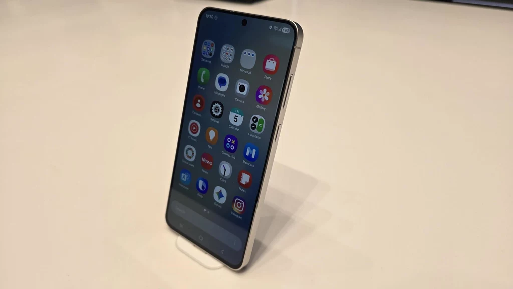 Smartfon Samsung Galaxy S25 FE prezentowany na IFA 2025 w Berlinie. Smartfon ustawiony pionowo na jasnej powierzchni, ekran urządzenia wypełniony kolorowymi ikonami aplikacji.