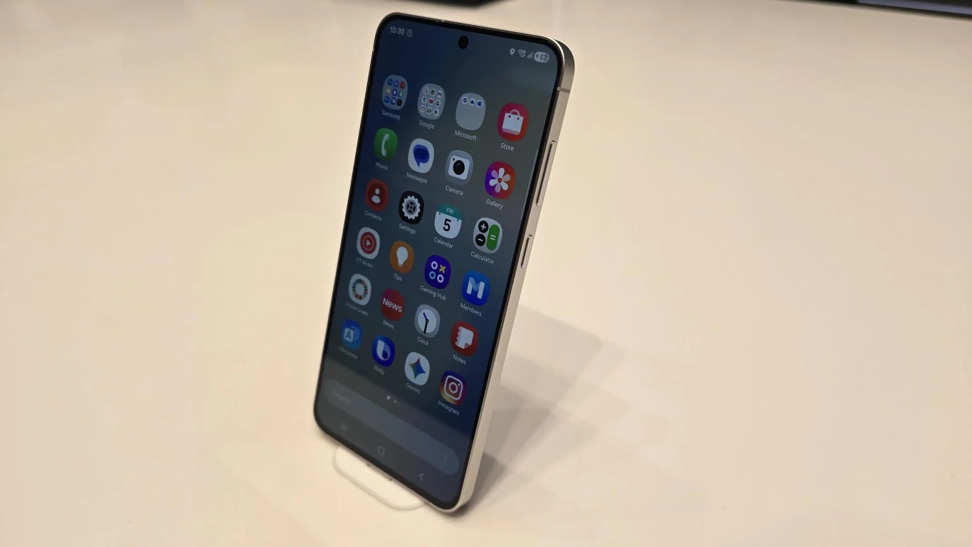 Smartfon ustawiony pionowo na jasnej powierzchni, ekran urządzenia wypełniony kolorowymi ikonami aplikacji.